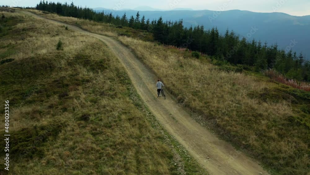 Man with bike mountain view doing active sport hilly road woods background