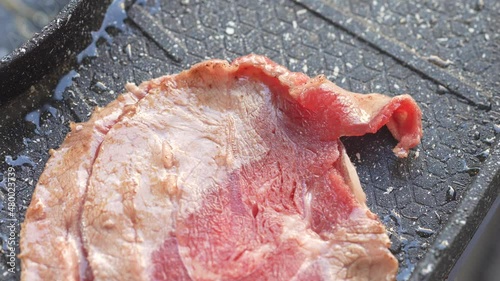 Close up a pork slices with chopsticks on electric grill pan.