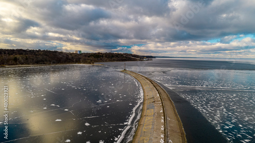 Aerial view of a pier with a lighthouse on a frozen lake