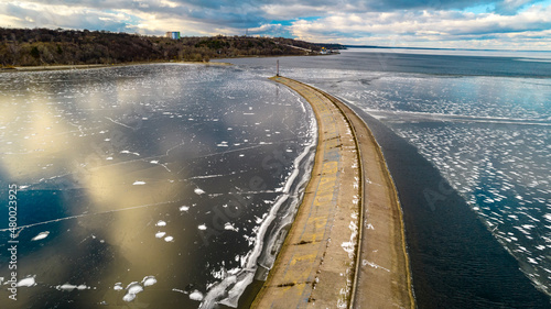 Aerial view of a pier with a lighthouse on a frozen lake