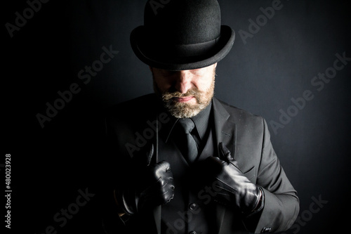 Portrait of Menacing Man in Dark Suit and Leather Gloves Scowling Meanly. British Gangster or Mafia Hit Man.