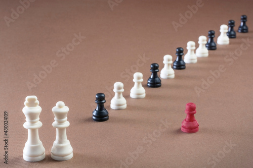 Chess pieces with one pawn isolated from the crowd