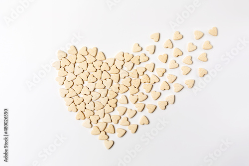 Heart-shaped little sweet cookies in form of dissolving heart on white background