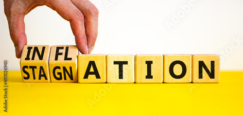 Inflation and stagnation symbol. Businessman turns cubes, changes the word inflation to stagnation. Beautiful yellow table, white background, copy space. Business, inflation and stagnation concept. photo