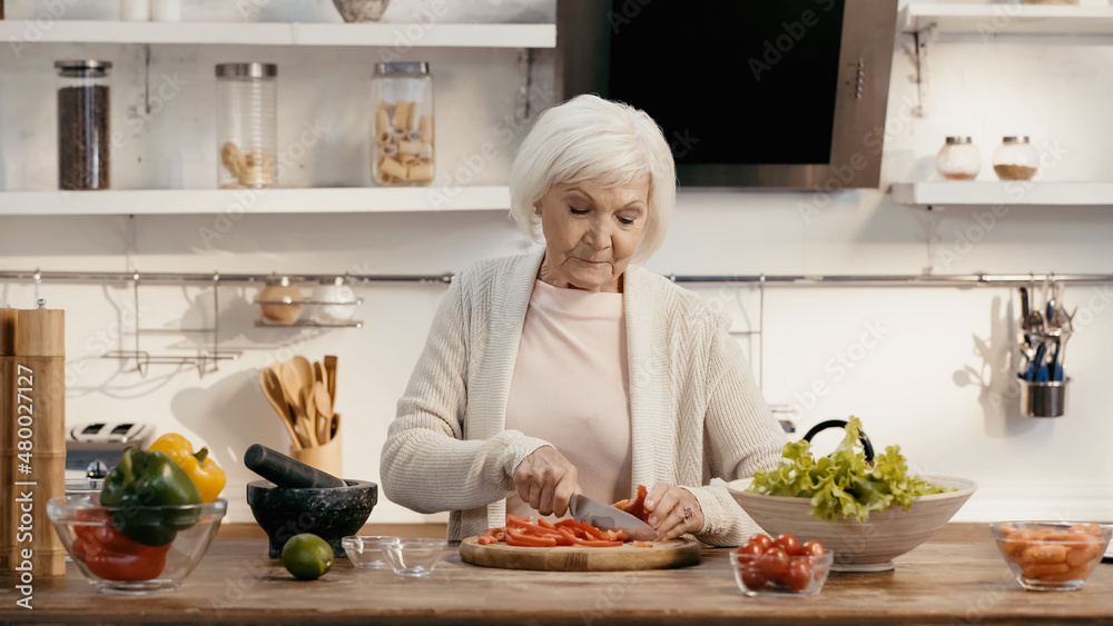 elderly woman preparing thanksgiving dinner and cutting bell pepper in kitchen. elderly woman preparing thanksgiving dinner and cutting bell pepper in kitchen.