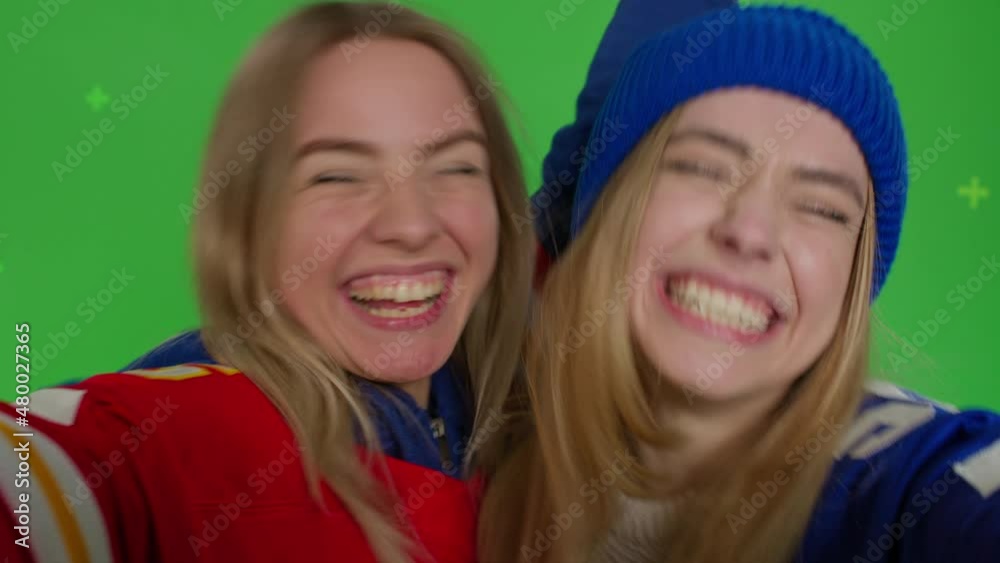 Two girls making selfie. Funny hipster females making self portrait . Young women in casual clothes having fun in front of green screen background. Chroma key Two girls making selfie. Funny hipster females making self portrait . Young women in casual clothes having fun in front of green screen background. Chroma key
