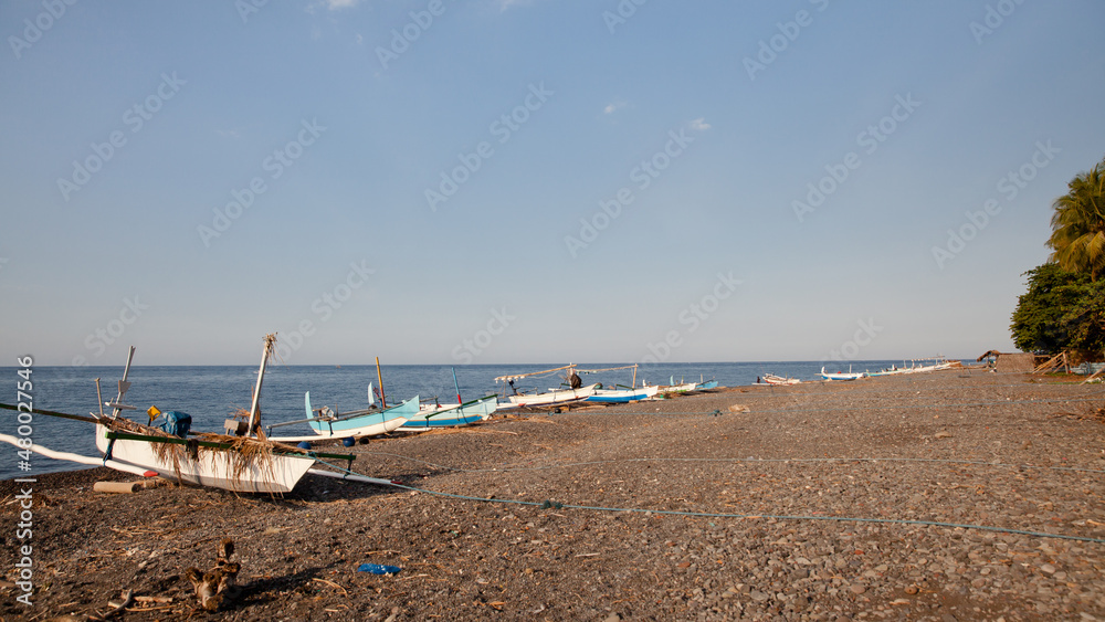 Fishing boats on the beach of Bali island. Sea and black volcanic sand. Fishing boats on the beach of Bali island. Sea and black volcanic sand.
