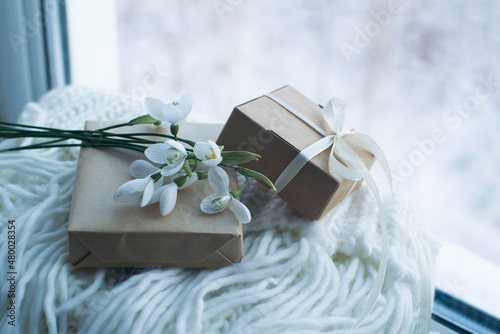 gift boxes, a bouquet of snowdrops on a white knitted scarf. congratulations on March 8, gift to mom, romantic background.