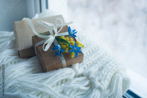 gift boxes, bouquet of spring flowers on white knitted scarf. congratulations on March 8, gift to mom, romantic background.