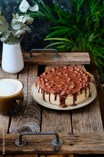 Cake pigeon's milk. Sponge cake and tender soufflé, creamy mousse. Garnished with milk chocolate and peanut. Side view, wooden background and coffee. © Lyudmila