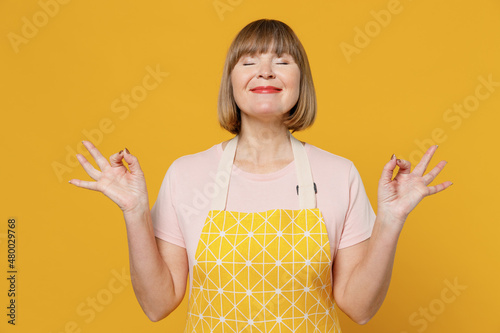 фотографія Elderly tranquil spiritual housekeeper housewife woman in orange apron hold spre