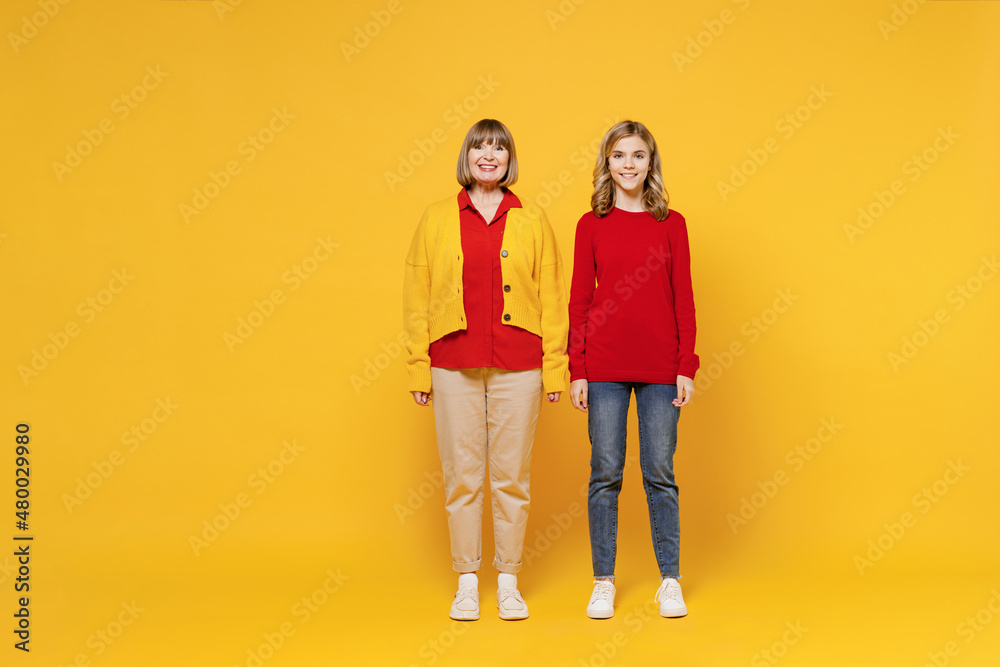 Full body smiling happy cool woman 50s in red shirt have fun with teenager girl 12-13 years old. Grandmother granddaughter look camera isolated on plain yellow background. Family lifestyle concept Full body smiling happy cool woman 50s in red shirt have fun with teenager girl 12-13 years old. Grandmother granddaughter look camera isolated on plain yellow background. Family lifestyle concept