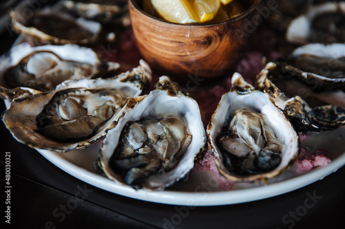 Fresh oysters on plate, served table with oysters, lemon in restaurant. Gourmet food