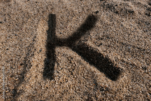 English alphabet. Sand on the beach. The letter K