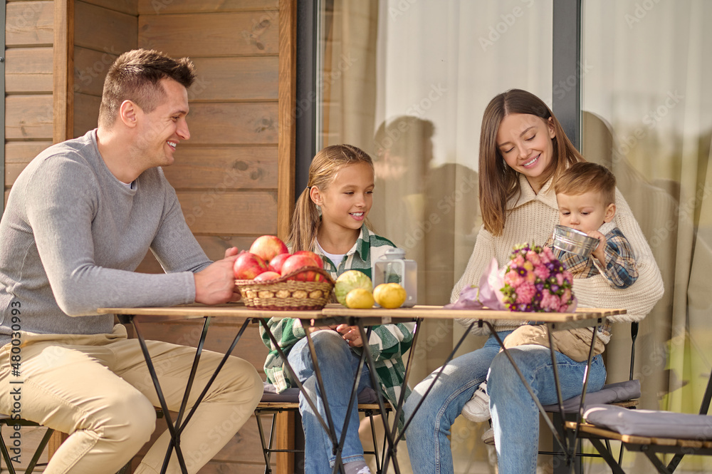 Man girl and woman looking at child sitting at table Man girl and woman looking at child sitting at table