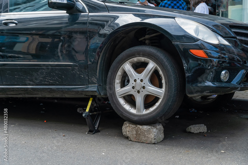 Close-up of a car on a jack, the wheel is on a brick © yaroslav1986