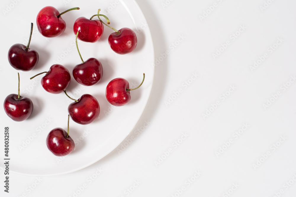 Cerezas dulces fruta en un plato blanco y fondo blanco. Vista superior Cerezas dulces fruta en un plato blanco y fondo blanco. Vista superior