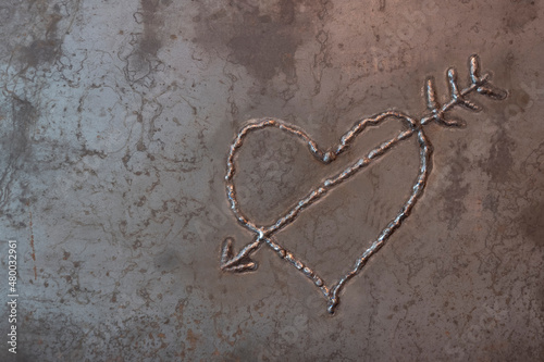 A heart pierced by Cupid's arrow. Image on a steel sheet by electric welding.
