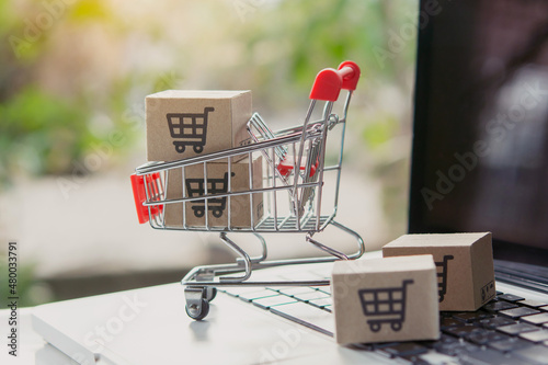 Shopping online. Cardboard box with a shopping cart logo in a trolley on laptop keyboard. Shopping service on The online web. offers home delivery.