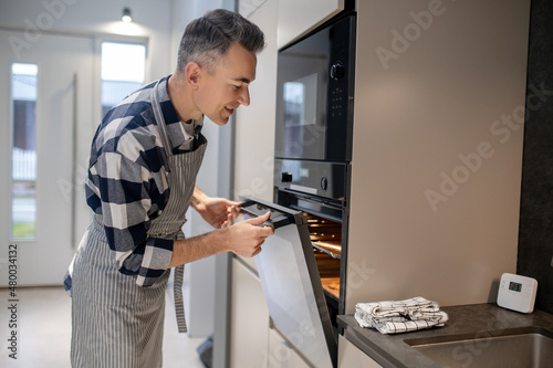 Man sideways to camera looking into open oven