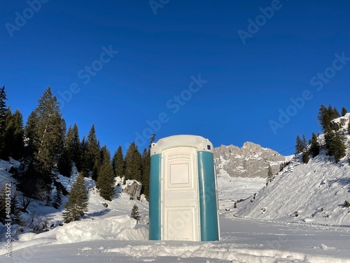 Portable chemical toilet in idyllic snow-covered winter landscape.  photo