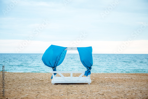 gazebo on the beach at sunset with folding blue curtains, no people 