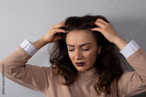 Stressed unhappy woman holding her head in her hands, suffering from grief problems
