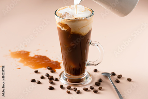 Pouring milk in ice coffee, refreshing summer cold coffee drink