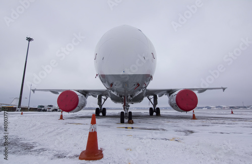 A jet passenger plane stands in the snowy parking lot of the airport in winter with plugs on the engines 