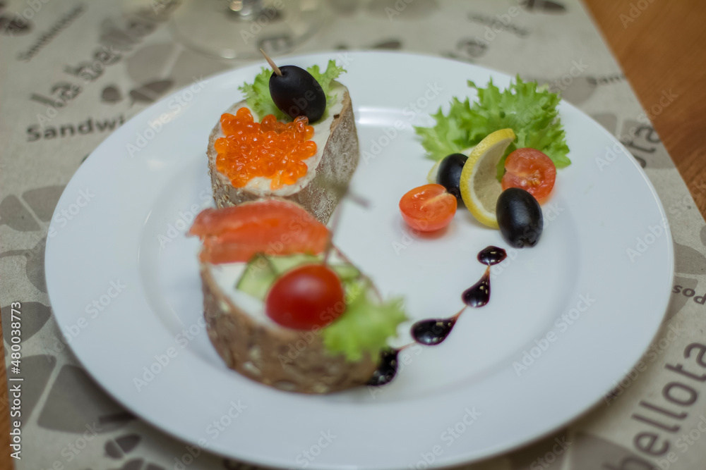 Macro shot, bread and butter with red caviar and olives on a plate, a sandwich Macro shot, bread and butter with red caviar and olives on a plate, a sandwich
