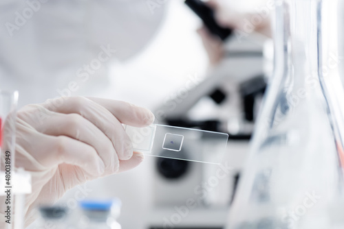 cropped view of blurred scientist working with laboratory slide, omicron variant concept.