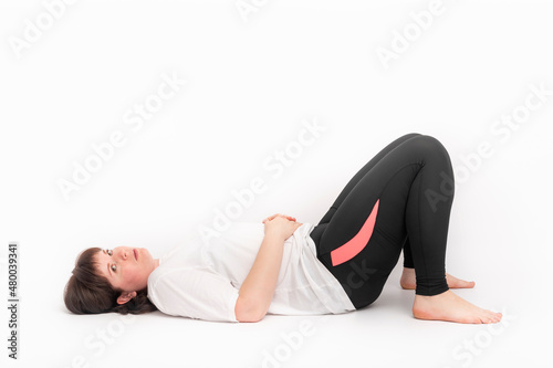 Plus size woman in sports t-shirt and leggings goes in for sports. Healthy lifestyle concept. Girl is tired and lies on back after training.