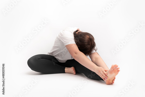 Fototapeta Naklejka Na Ścianę i Meble -  Woman does gymnastics and performs an exercise to develop flexibility. Portrait of girl practicing yoga on white background.