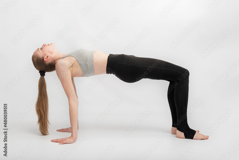 Young slender woman practices yoga on white background. Beautiful athletic body. Ardha Purvottanasana. Reverse Table Pose.