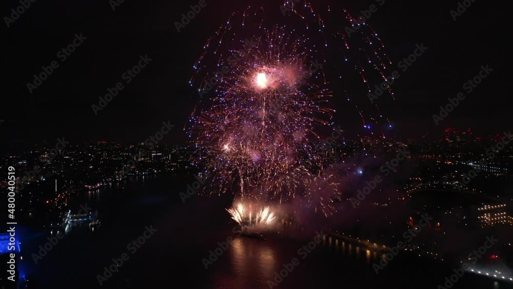 Aerial drone spectacular night video of firework show with dazzling colours glowing over river Thames to celebrate new year's eve, London, United Kingdom
