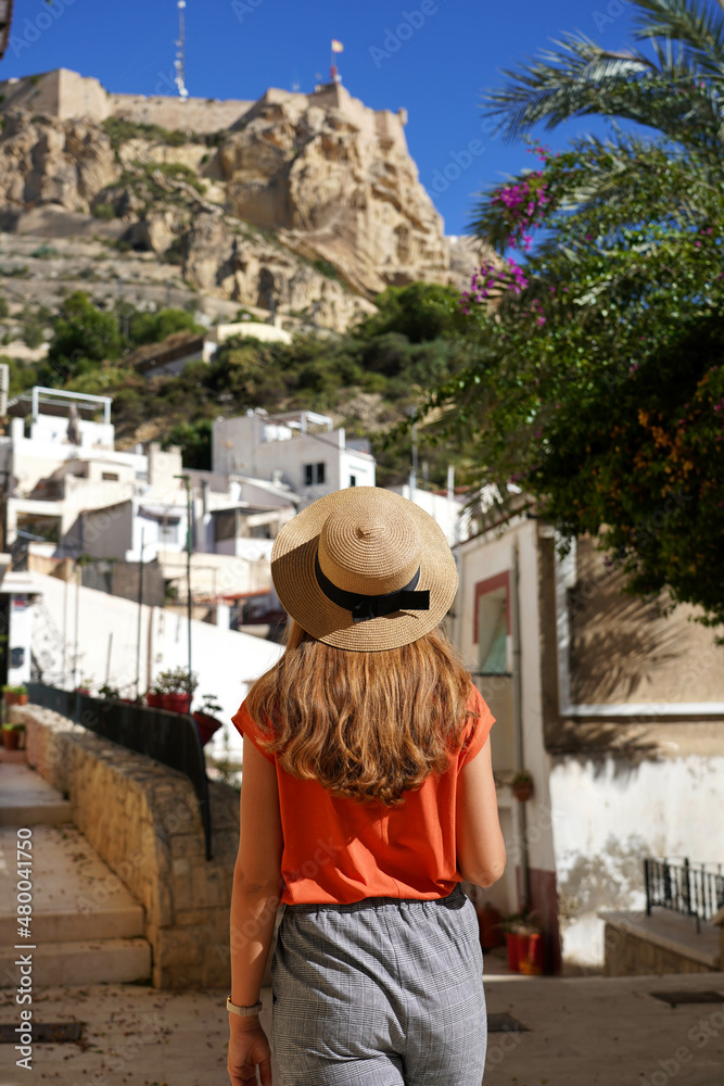 Tourist woman walking in the neighborhood Santa Cruz looking at Mount Benacantil with Santa Barbara castle in Alicante, Spain