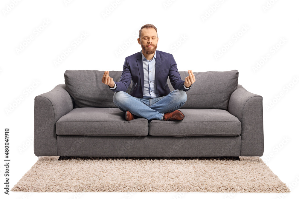 Young man in casual elegant clothes meditating on a sofa Young man in casual elegant clothes meditating on a sofa