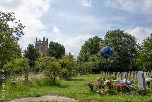 blue Fathers day balloon hanging on grave with flowers at graveyard by church photo