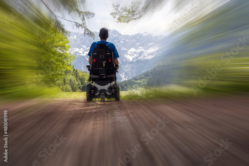 Man on a wheelchair relaxing in motion blur lloking at nature and mountains. photo