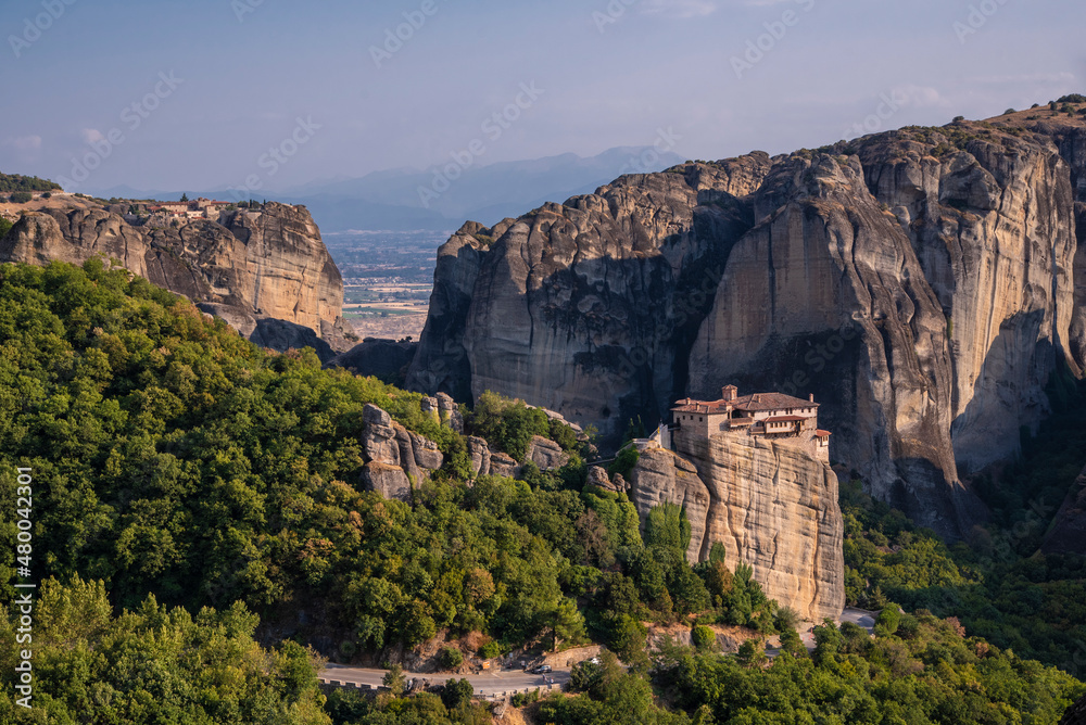 Beautiful scenic view of Orthodox Monastery of Varlaám (Varlaam) on cliff,immense monolithic pillar, at the background of stone wall and rock formations of Meteora mountain, Greece.