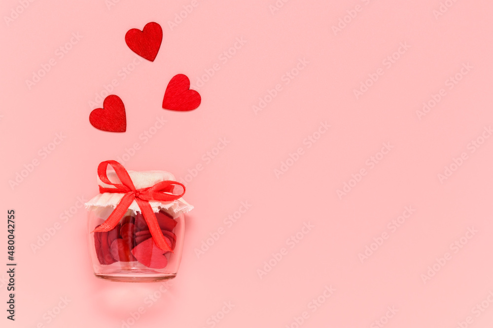 Red hearts in jar with bow knot on pink pastel background. Romantic heart composition for Valentines day or mothers day card. Love concept, copyspace for text Red hearts in jar with bow knot on pink pastel background. Romantic heart composition for Valentines day or mothers day card. Love concept, copyspace for text