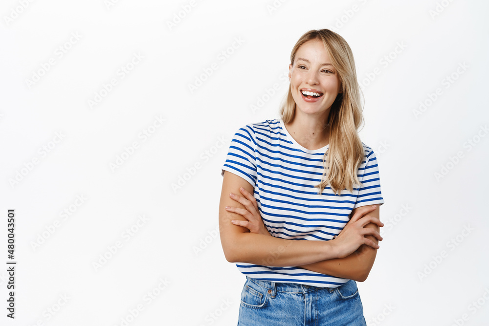 Fototapeta premium Beautiful happy girl laughing and smiling. Modern scandinavian woman posing against white background, looking happy, wearing summer clothes