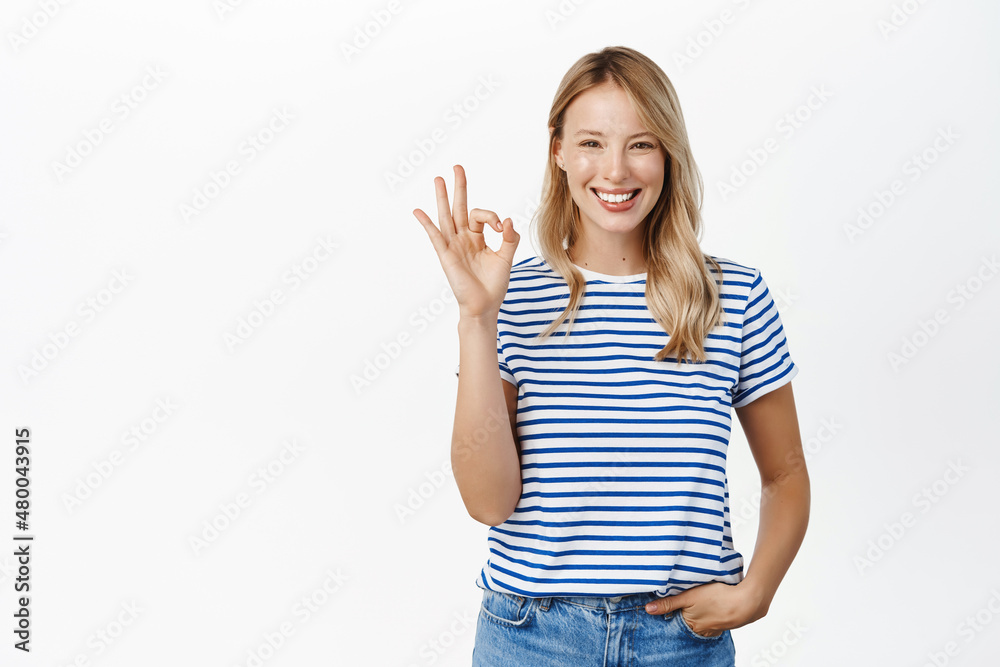Perfect, very good. Smiling attractive young woman showing okay, ok gesture and looking satisfied, recommending great product, praise or approve smth, white background Perfect, very good. Smiling attractive young woman showing okay, ok gesture and looking satisfied, recommending great product, praise or approve smth, white background