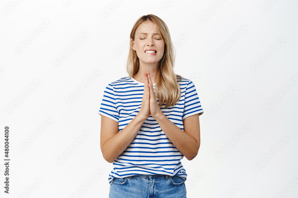 Hopeful young woman, girl student begging, asking and say please, wishing for smth, praying, standing in pleading pose against white background Hopeful young woman, girl student begging, asking and say please, wishing for smth, praying, standing in pleading pose against white background