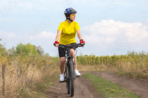 beautiful and happy woman cyclist rides a bicycle on the road in nature. Healthy lifestyle and sports. Leisure and hobbies