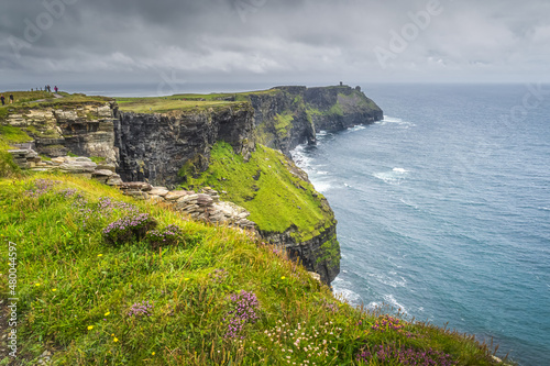 Group of people or tourists hiking and sightseeing iconic Cliffs of Moher, popular tourist attraction, Wild Atlantic Way, County Clare, Ireland