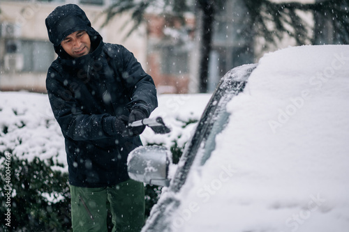 Middle aged man cleaning car from snow and ice