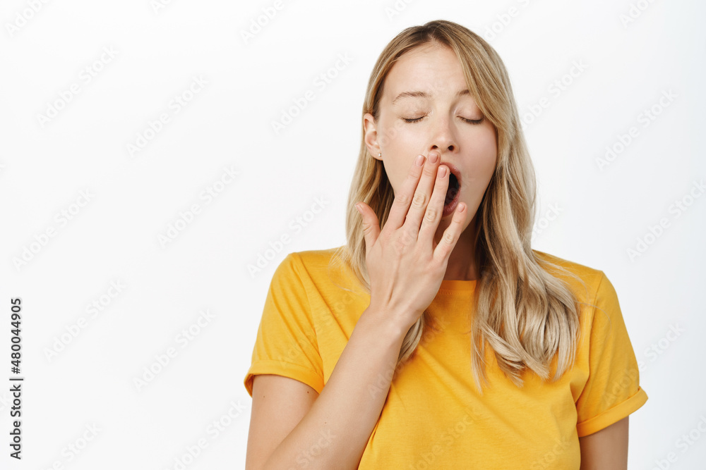 Portrait of tired girl student, young woman yawning, cover opened mouth, fatigue or boredom, standing over white background Portrait of tired girl student, young woman yawning, cover opened mouth, fatigue or boredom, standing over white background