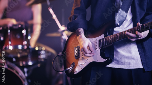 KYIV, UKRAINE - DECEMBER 30, 2021: cropped view of tattooed guitarist playing on stage.