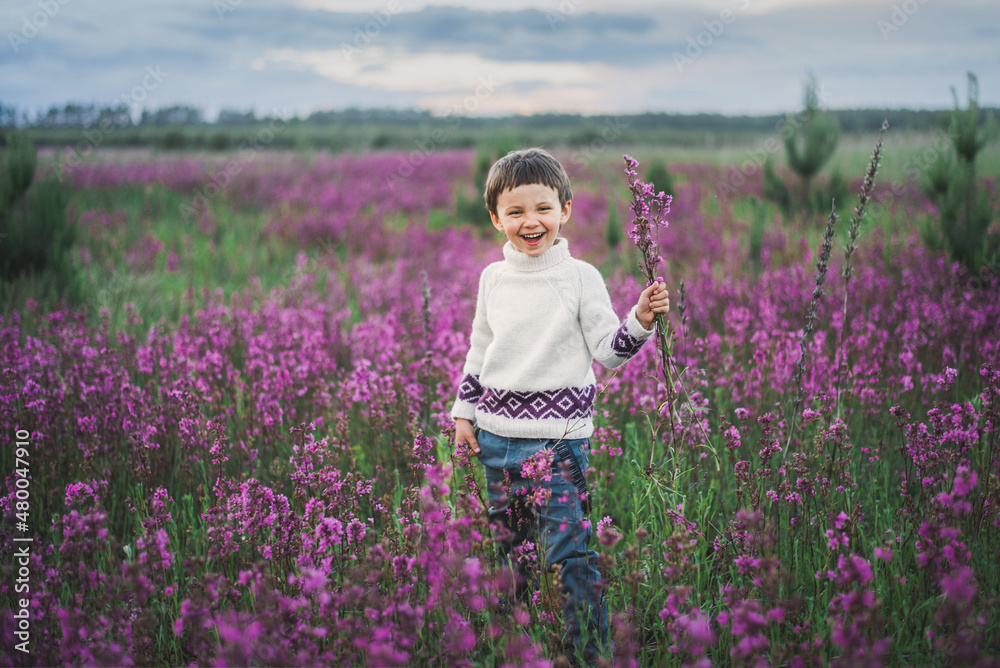 Φωτογραφία a boy stands in a field of purple flowers at sunset and holds a bouquet of flowers in his hands